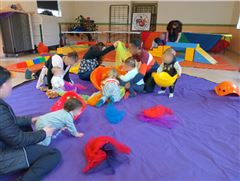 Enfants jouant avec leurs accompagnants sur un tapis de sol violet